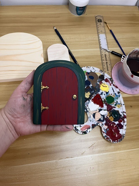 A Julenissen door being hand-painted on the workbench of a North Carolina art studio